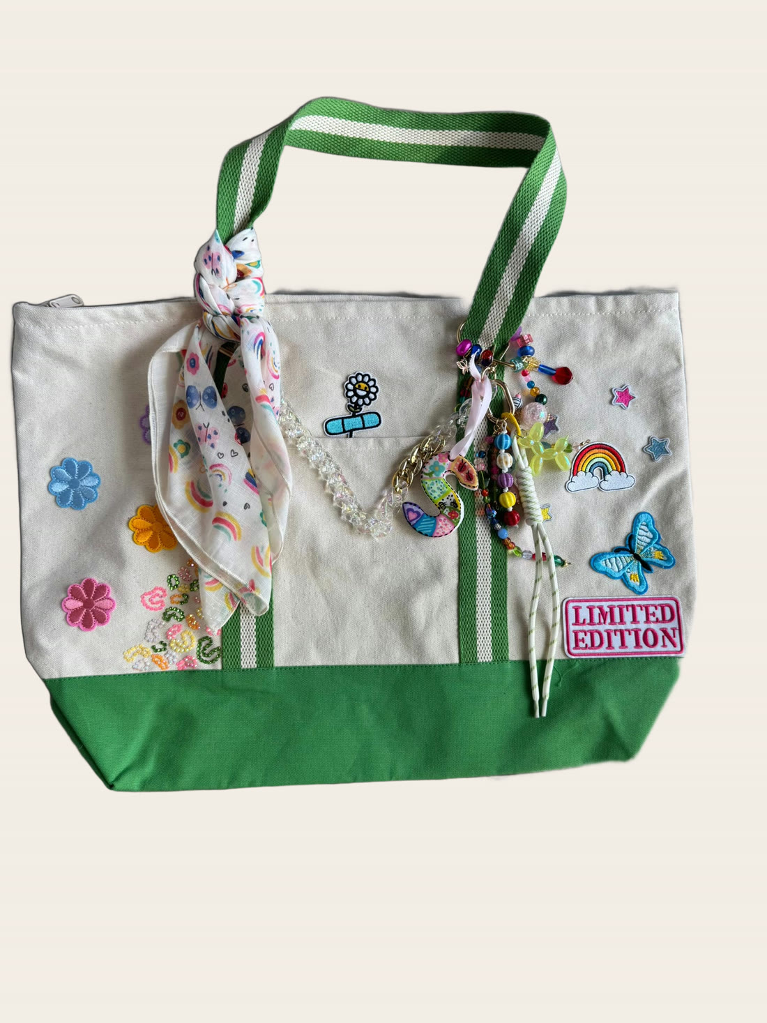 A cream and green canvas tote with rainbow, flower and butterfly patches and a LIMITED EDITION patch.